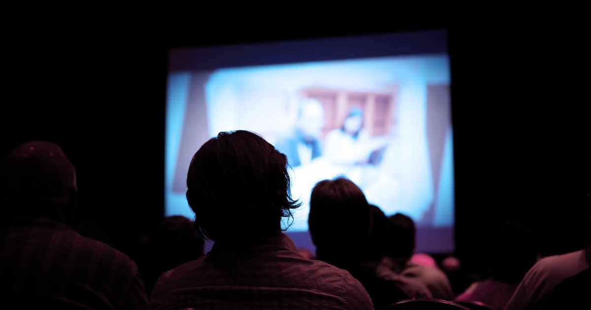 People watch a movie in a theater in this stock image.
