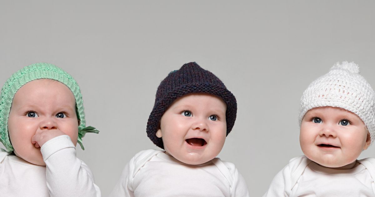 This stock photo pictures three babies in hats.