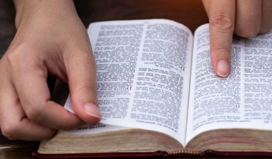 A man reads the Bible in the above stock image.