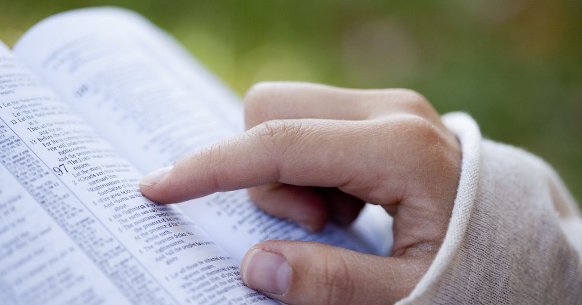 A woman reads the Bible in the above stock image.