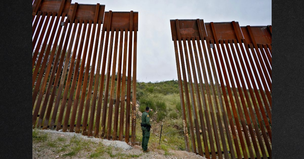 A U.S. Border Patrol agent looks into Mexico at a breach in the 30-foot-high border wall in Sasabe, Ariz.