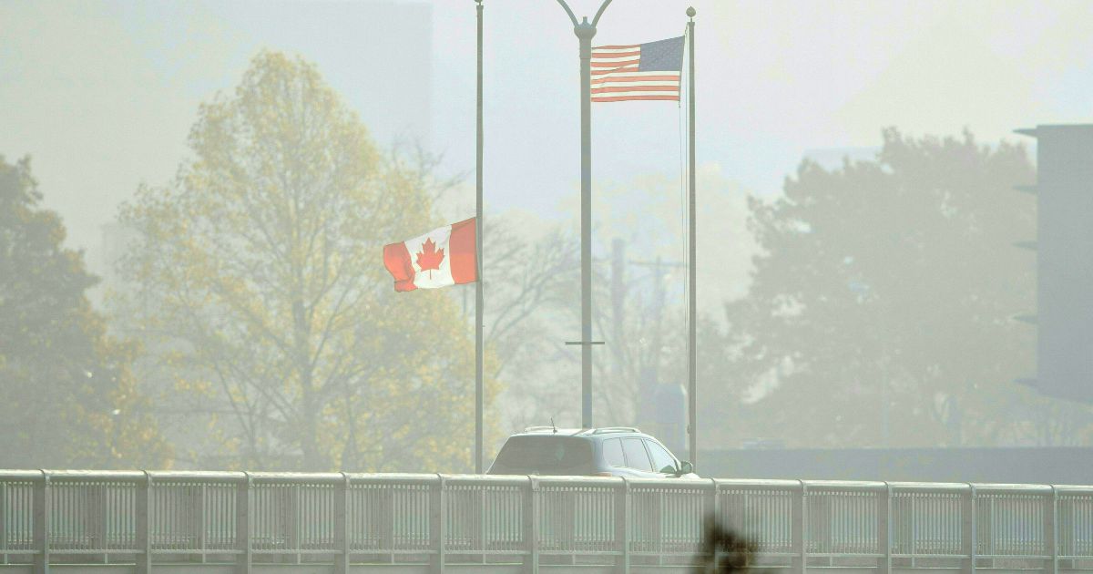 Travellers cross the Rainbow Bridge from Niagara Falls, Ontario, to Niagara Falls, New York through the fog in this file photo from November 2021. Canadian merchants complain their nation's COVID restrictions are hurting business.