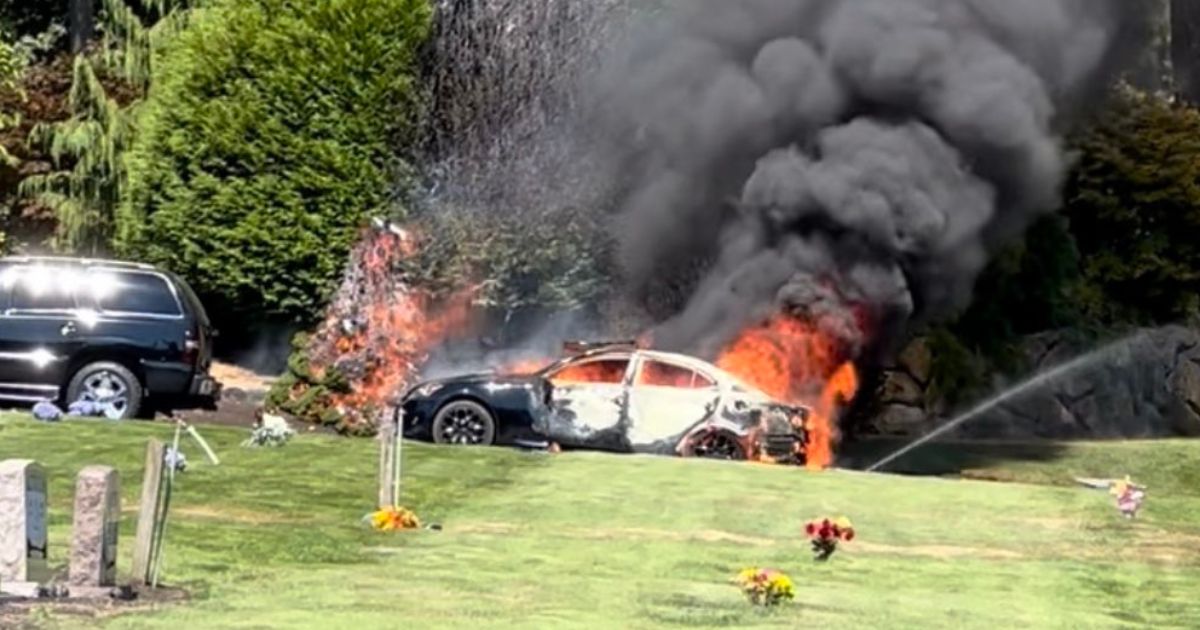 A car is on fire during a funeral at Mountain View Cemetery in Auburn, Washington.