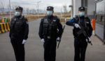 three Chinese police officers standing outside a detention center