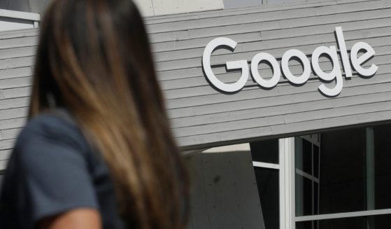 a woman walking below a Google sign