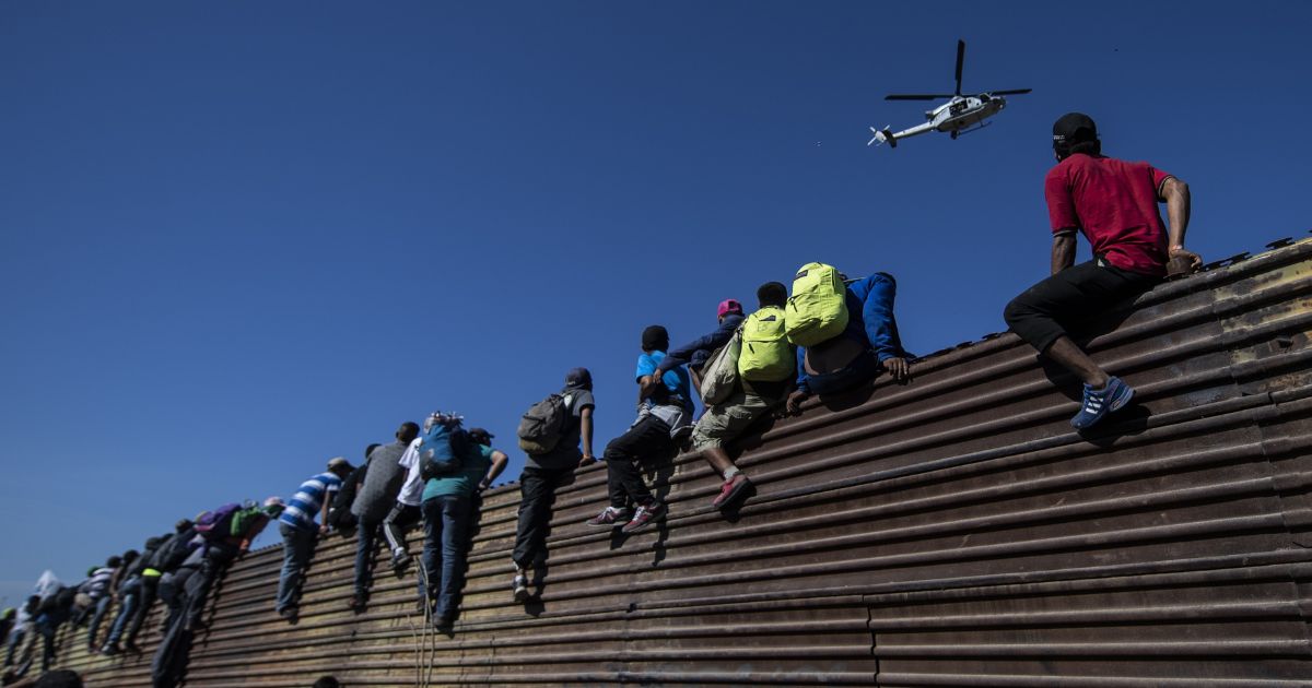 A group of illegal immigrant from Central America climb over a metal barrier on the U.S.-Mexico border near Tijuana, Mexico, on Nov. 25, 2018.