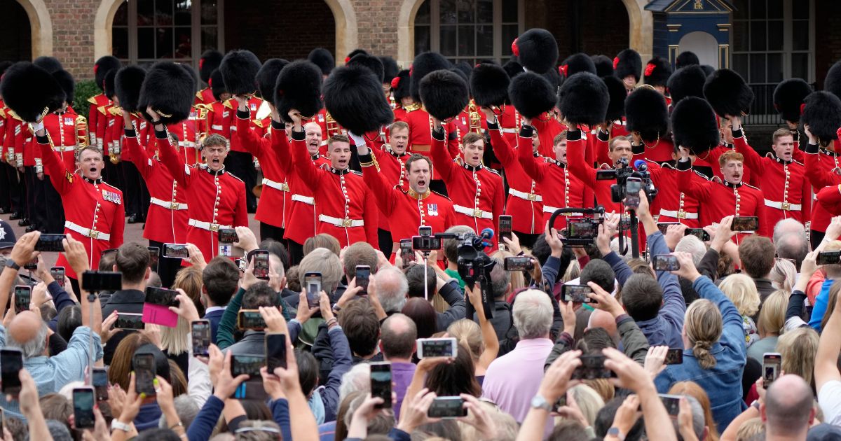 Members of the public gather as military personnel offer three cheers to the new king at St James's Palace in London on Saturday.