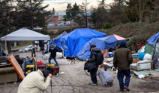 People walk through a homeless encampment in Seattle after smoking fentanyl on March 11.
