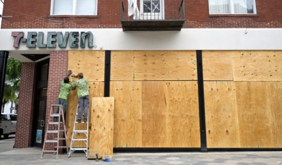 Workers on Tuesday board up the windows of a 7-Eleven convenience store in the Ybor City district of Tampa, Florida, in preparation as Hurricane Ian approached Florida's coast.
