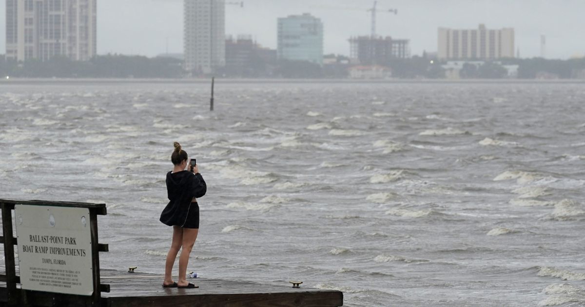 A woman takes photos of the surf on Tampa Bay ahead of Hurricane Ian on Wednesday in Tampa, Florida.