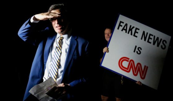 A man holds a sign that reads Fake News is CNN.