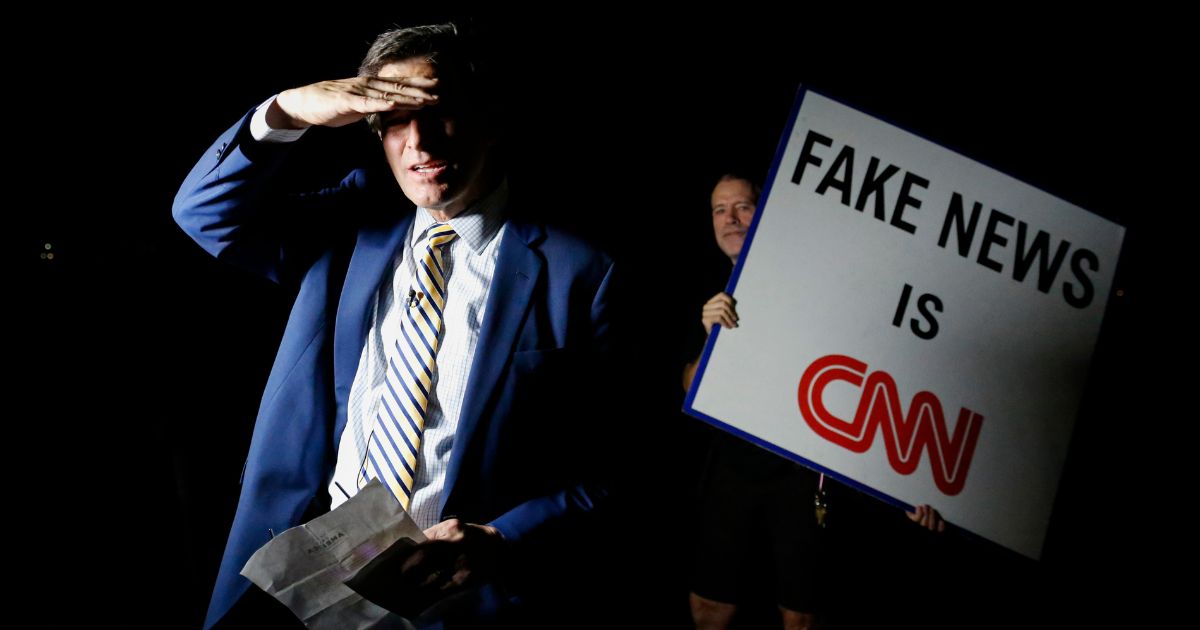 A man holds a sign that reads Fake News is CNN.