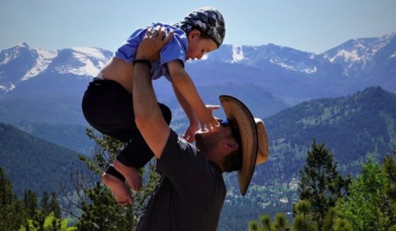 TJ Cook carries his son, Robbie, on his back, while traveling through national parks.