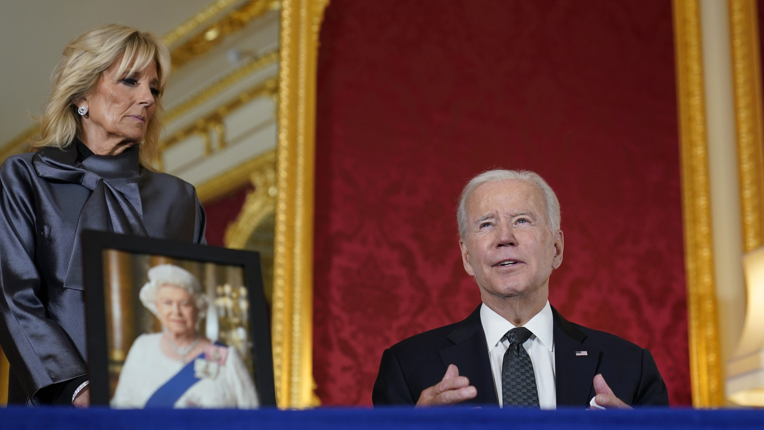 President Joe Biden, right, sits down to sign an official condolence book for Queen Elizabeth II at Lancaster House in London on Sunday.