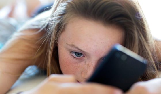 A girl uses a cellphone in this stock image.