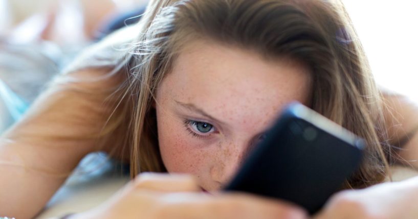 A girl uses a cellphone in this stock image.
