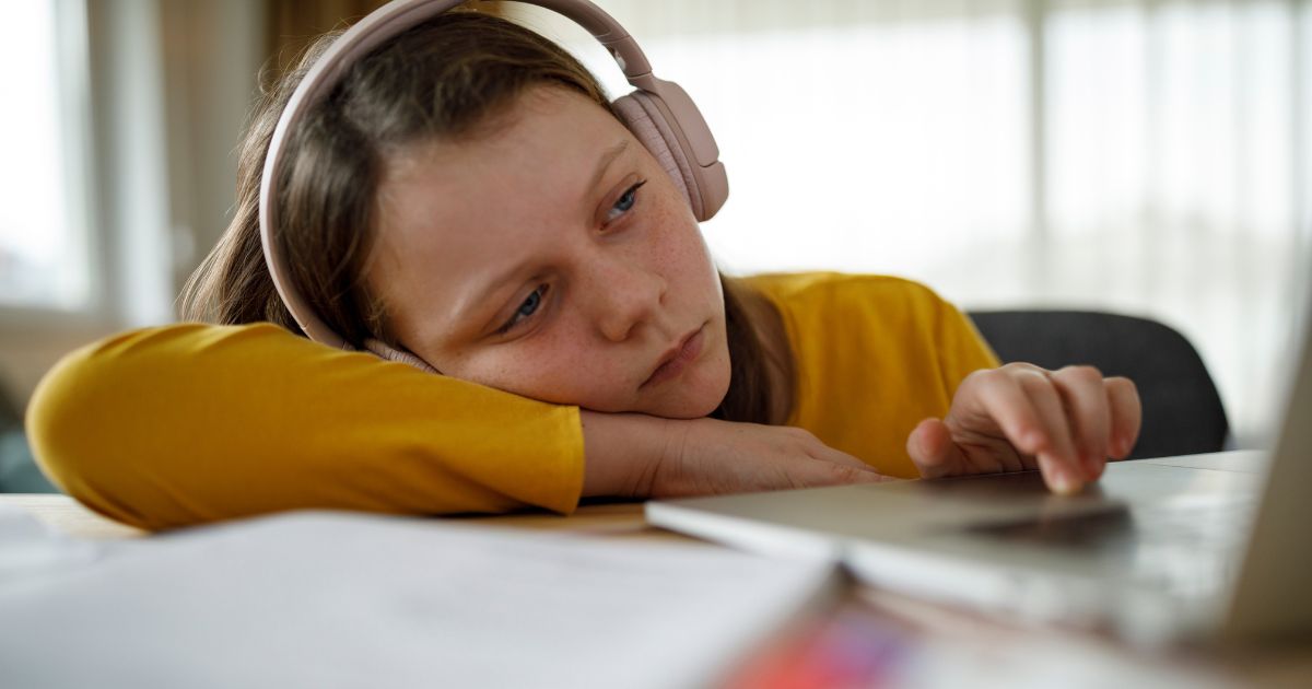 A girl participates in online school in the above stock image.