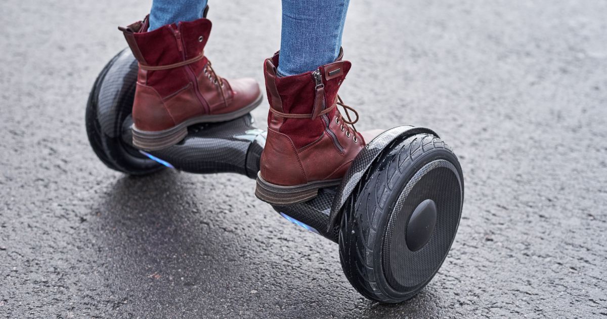 A woman stands on a hoverboard in the street.