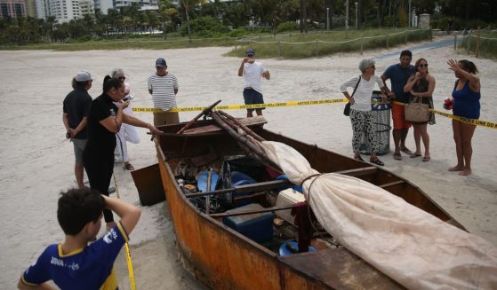 People look at a Cuban migrant boat on the beach