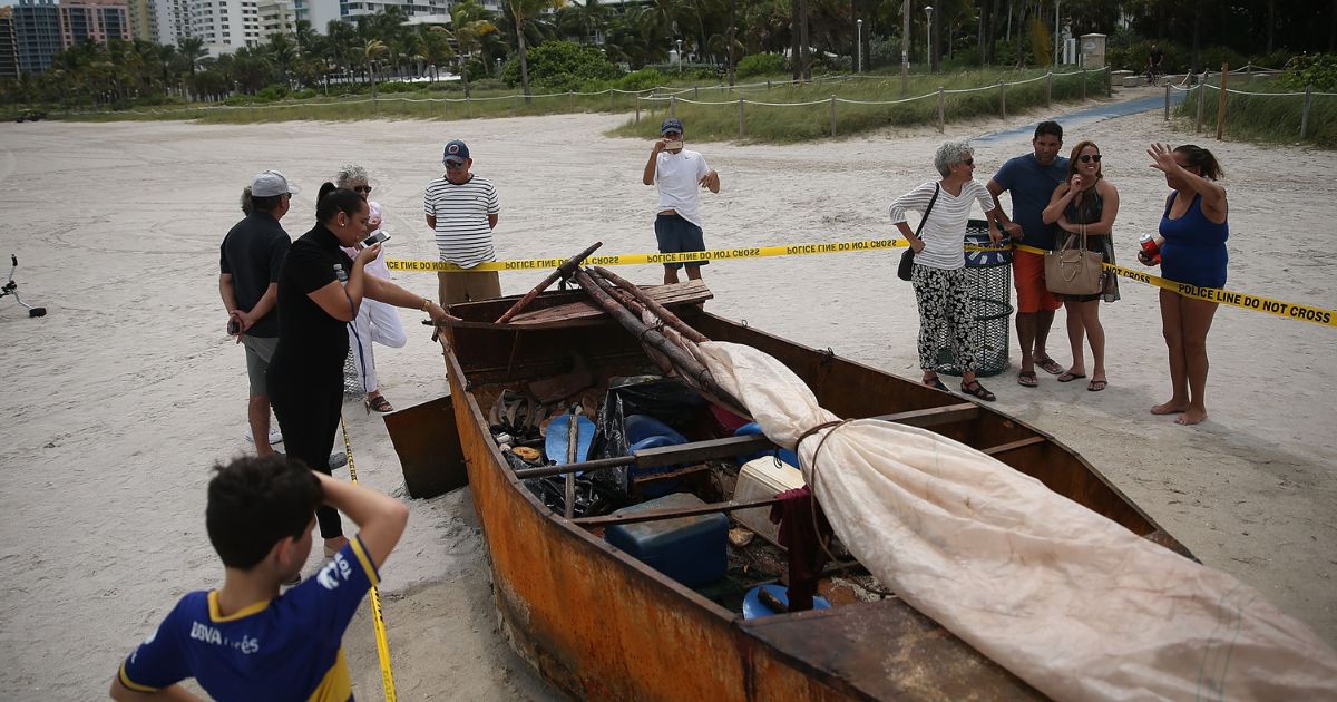 People look at a Cuban migrant boat on the beach
