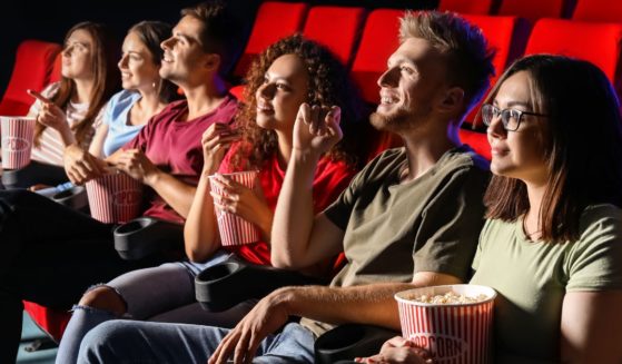 A group of people watch a movie in the above stock image.
