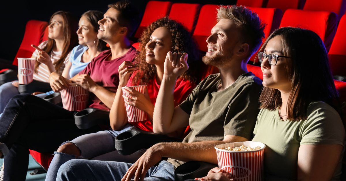 A group of people watch a movie in the above stock image.