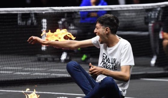 A climate change activist set his arm on fire after rushing the court during a Laver Cup tennis match in London on Friday.