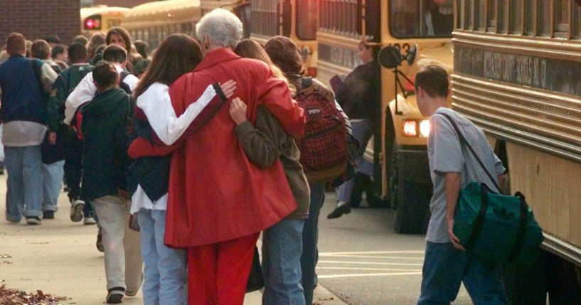 Students arriving at Heath High School in West Paducah, Kentucky, embrace an unidentified adult on Dec. 2, 1997, after student Michael Carneal opened fire at the school the day before, leaving three students dead and five wounded.