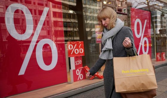 A woman walks with purchases past a store