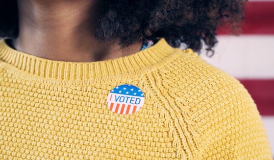 A woman wears an "I Voted" sticker in this stock image.