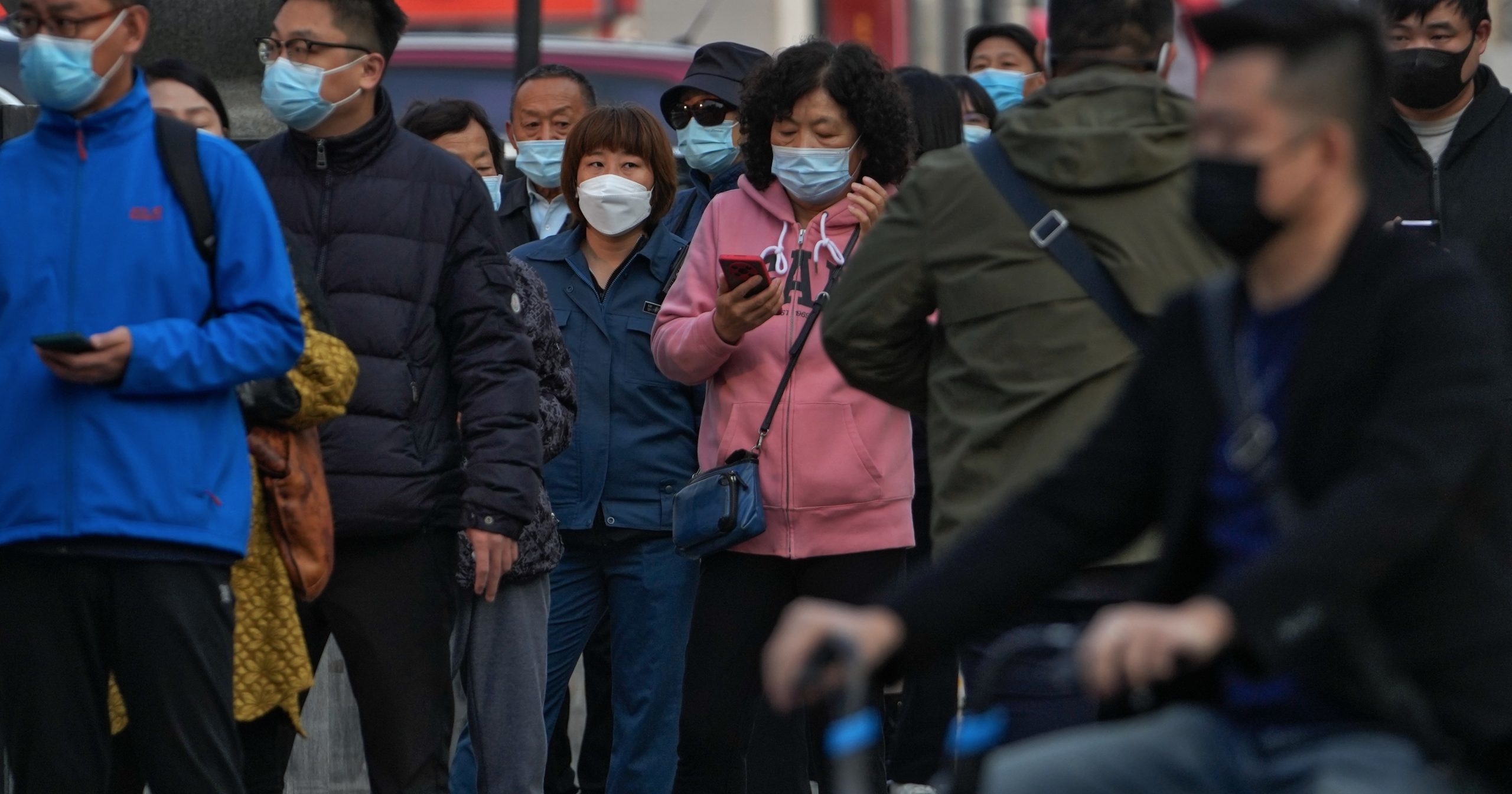 Residents wearing face masks wait in line to get their routine COVID-19 throat swabs at a coronavirus testing site in Beijing, China, on Tuesday.
