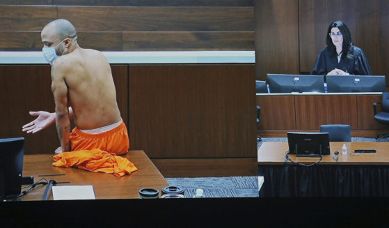 Darrell Brooks sits shirtless in an empty court room after being removed from the first day of his trial for continuously interrupting Waukesha County Circuit Judge Jennifer Dorow, on screen to the right. Brooks is accused of killing six people and injuring dozens more when he allegedly drove his SUV through a Christmas parade in Wisconsin last year.