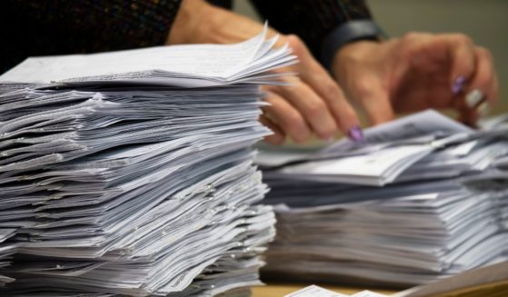 A woman counts a pile of paper ballots during an election.