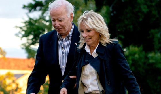 President Joe Biden, left, holds on to first lady Jill Biden, right, as they walk across the South Lawn of the White House on Oct. 5.