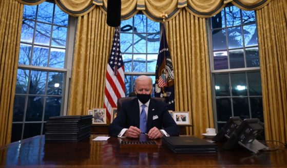 President Joe Biden sits down in the Oval Office of the White House to sign a series of orders on Inauguration Day, Jan. 20, 2021.
