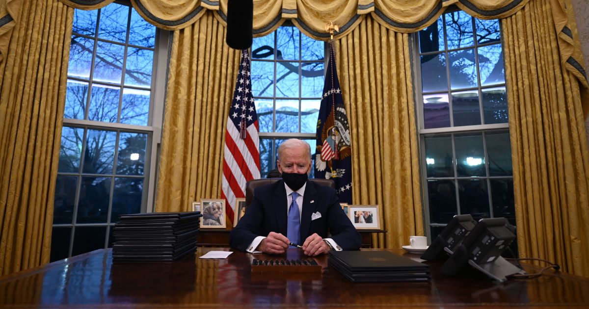 President Joe Biden sits down in the Oval Office of the White House to sign a series of orders on Inauguration Day, Jan. 20, 2021.