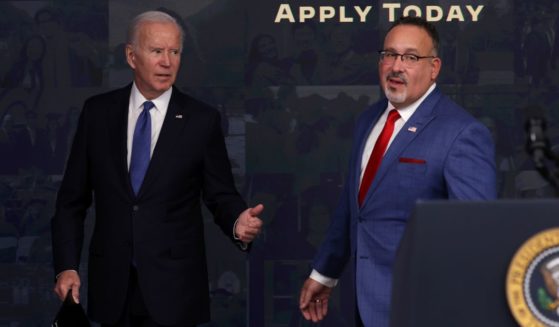 President Joe Biden, walking alongside Secretary of Education Miguel Cardona, freezes when asked a question about private student loans following an event about the administration's student debt relief program in the South Court Auditorium of the Eisenhower Executive Office Building in Washington on Monday.