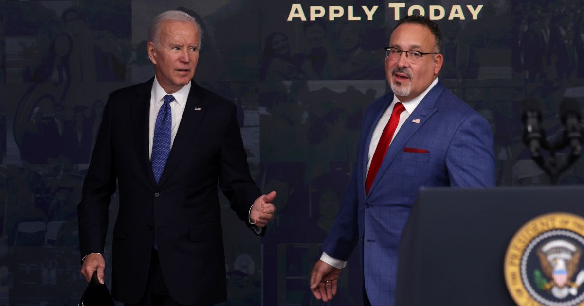 President Joe Biden, walking alongside Secretary of Education Miguel Cardona, freezes when asked a question about private student loans following an event about the administration's student debt relief program in the South Court Auditorium of the Eisenhower Executive Office Building in Washington on Monday.