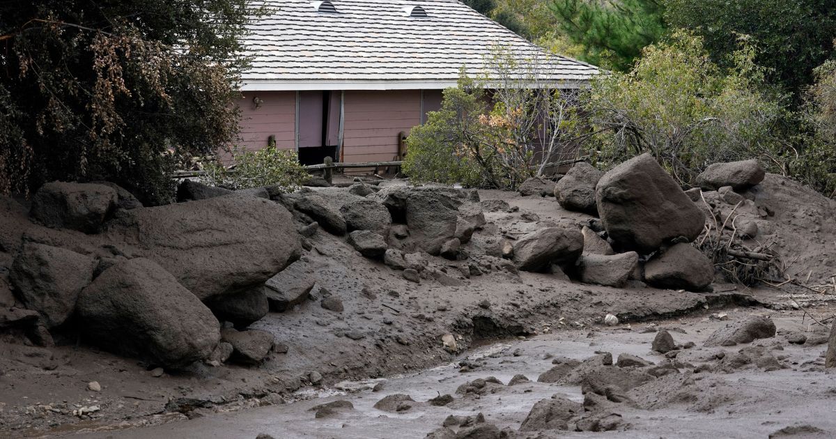 The front yard of a property covered in mud in the aftermath of a mudslide
