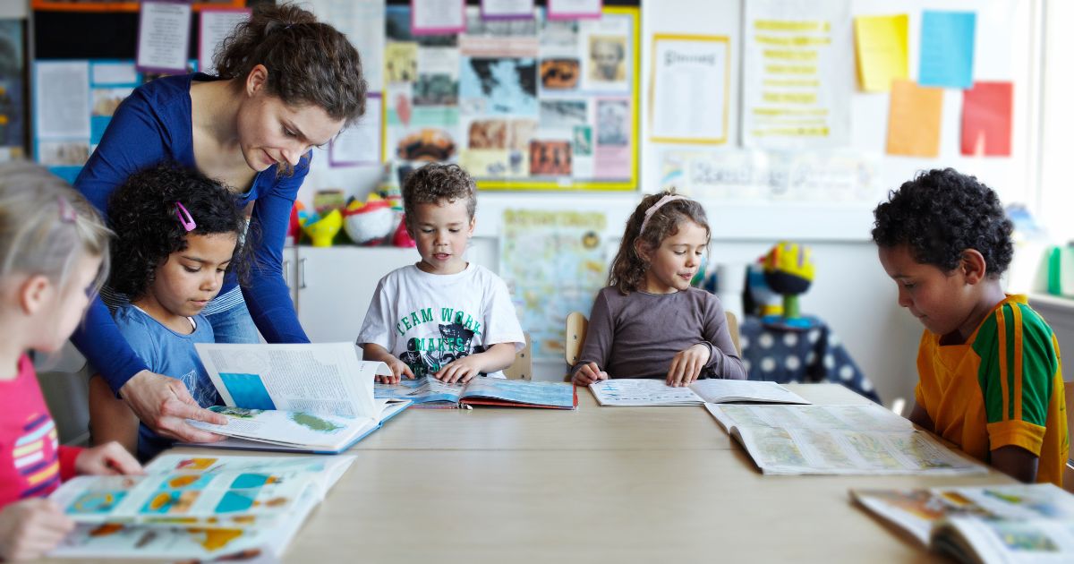 In this stock photo a teacher reads books with her students.