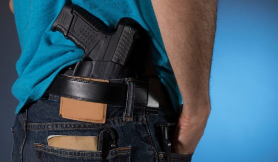 This stock image shows a man standing with a handgun in a holster.