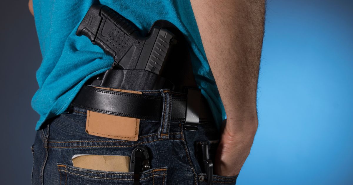 This stock image shows a man standing with a handgun in a holster.