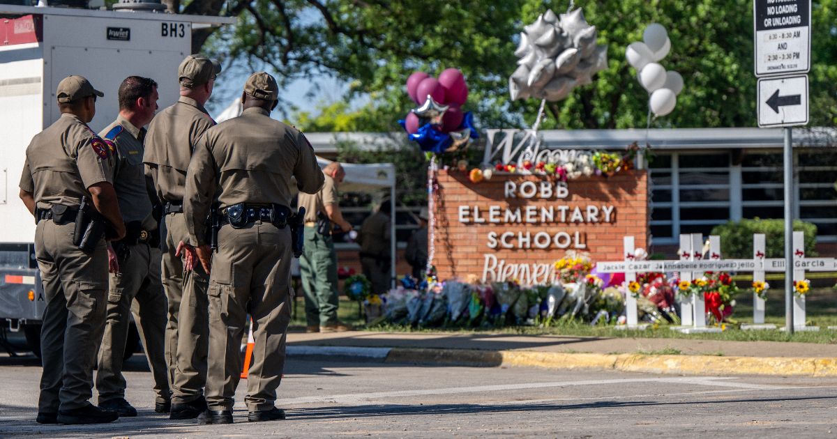 Law enforcement officers stand looking a memorial outside of Robb Elementary School in Uvalde, Texas, on May 26.