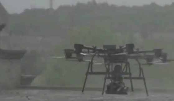 A drone carries the robotic dog, which is equipped with a machine gun, in a demonstration video.