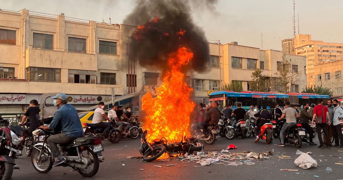 People gather next to a burning motorcycle in the capital Tehran, Iran, on Saturday.