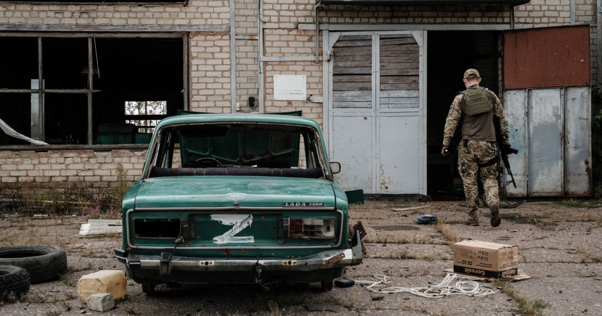 A Ukrainian army press officer stands next to a destroyed car in the town of Lyman in the Donetsk region on Wednesday.
