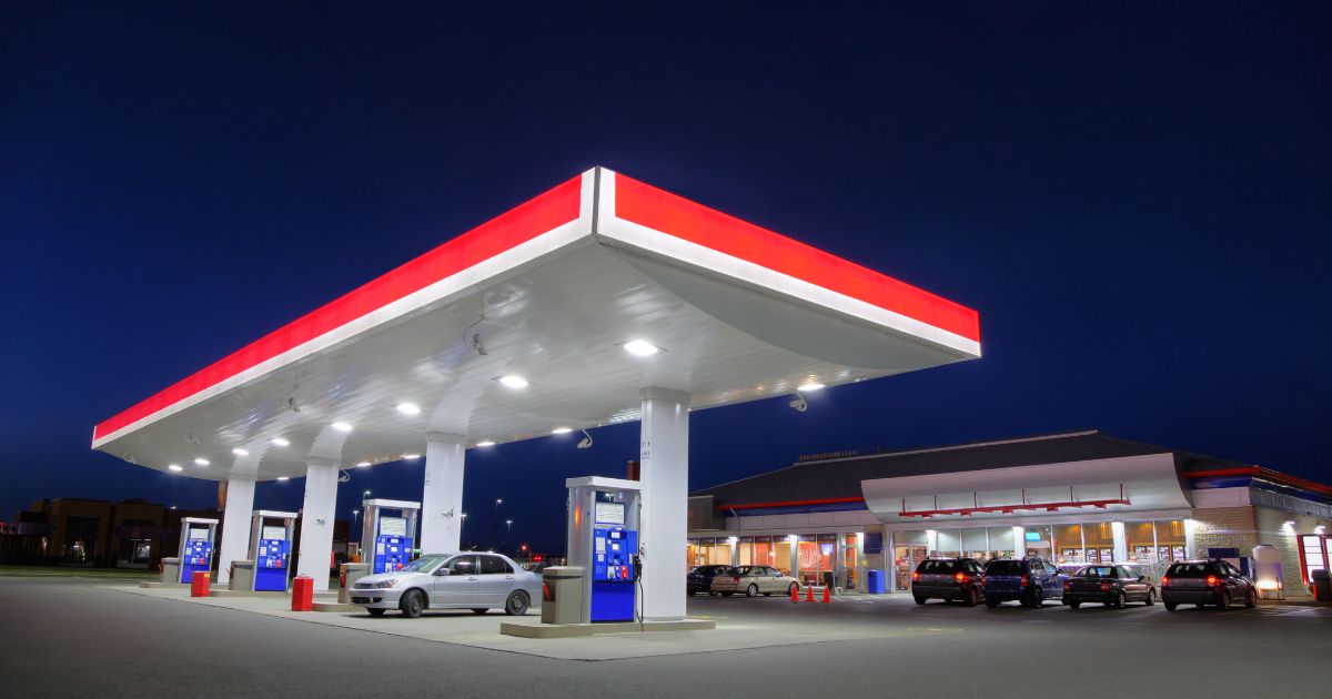 A car refuels as a gas station during the night.