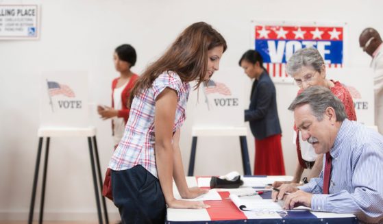 A photo illustration depicts a voter checking in with a poll worker before voting.