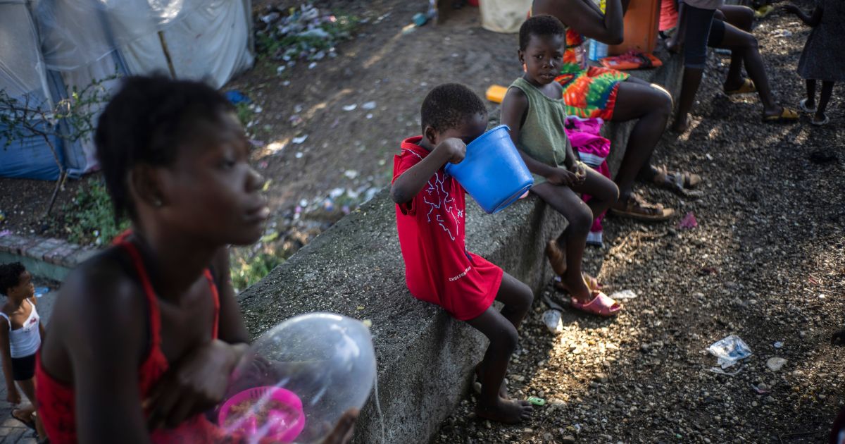 A child eats from a bucket on Oct. 20 at the Hugo Chavez public square, which has been transformed into a refuge for families forced to leave their homes due to clashes between armed gangs in Port-au-Prince, Haiti.