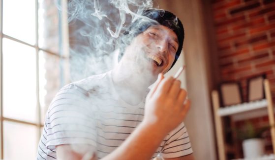 A man smoking marijuana with a smile.